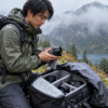 雨天の登山で交換レンズとカメラバッグを保護する撮影者