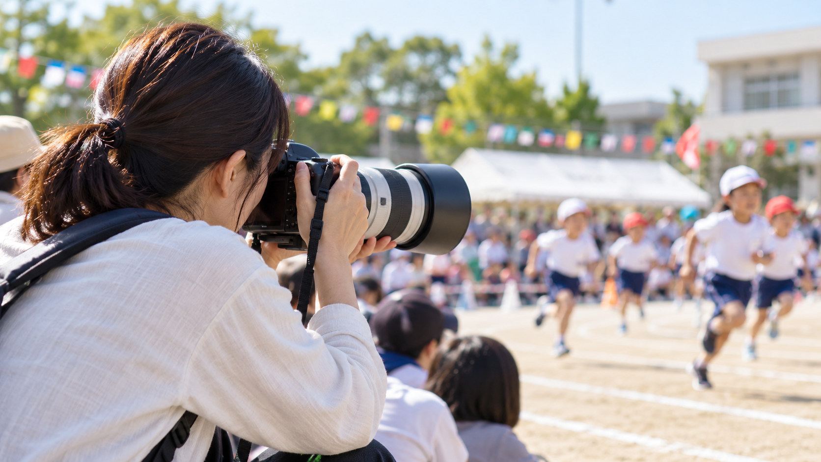 運動会で望遠レンズを使って子どもを撮影する日本人女性