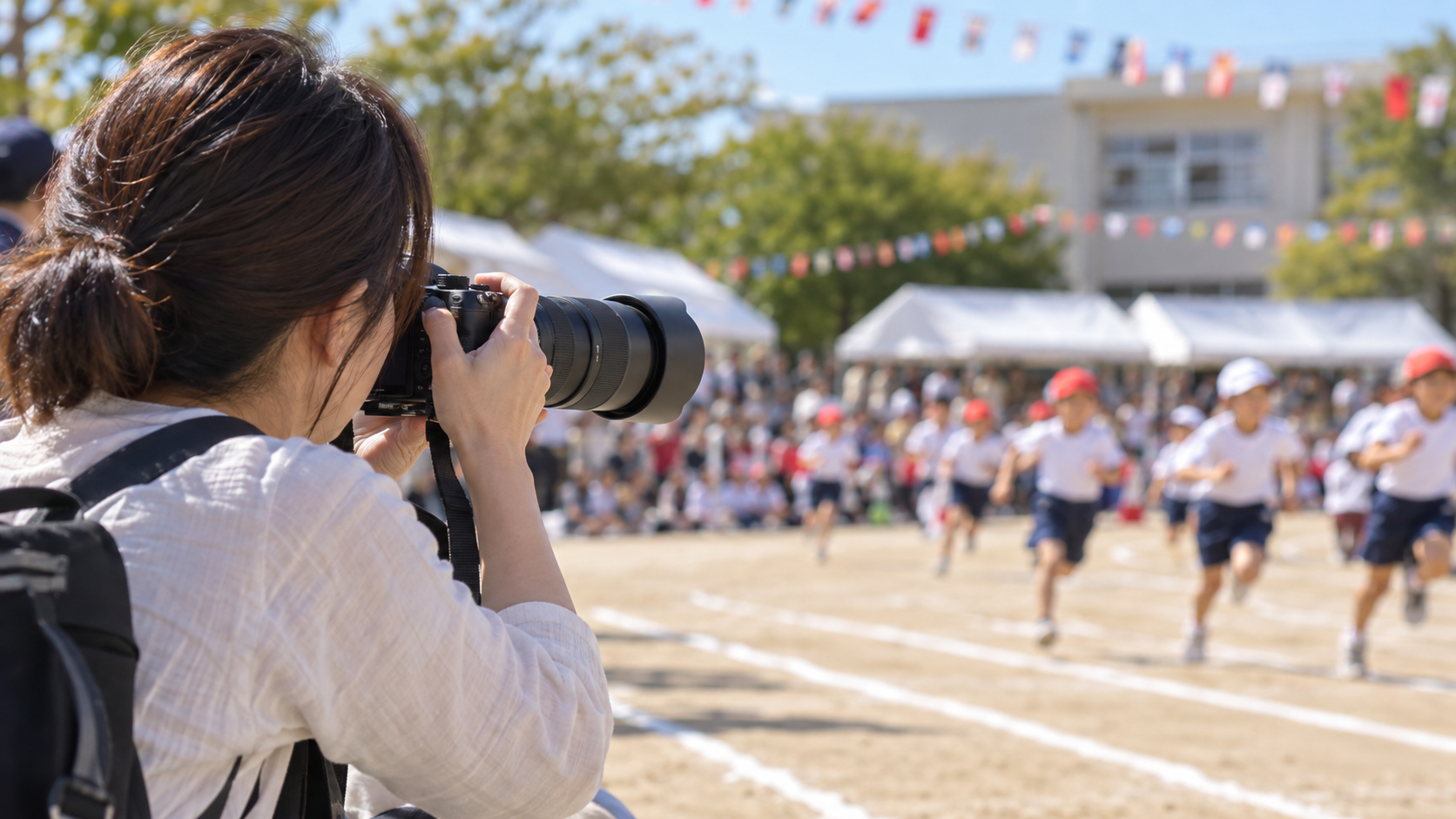 運動会で望遠ズームレンズを使って子どもを撮影する日本人女性