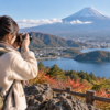 軽量ミラーレスカメラで富士山と湖を撮影する日本人旅行者