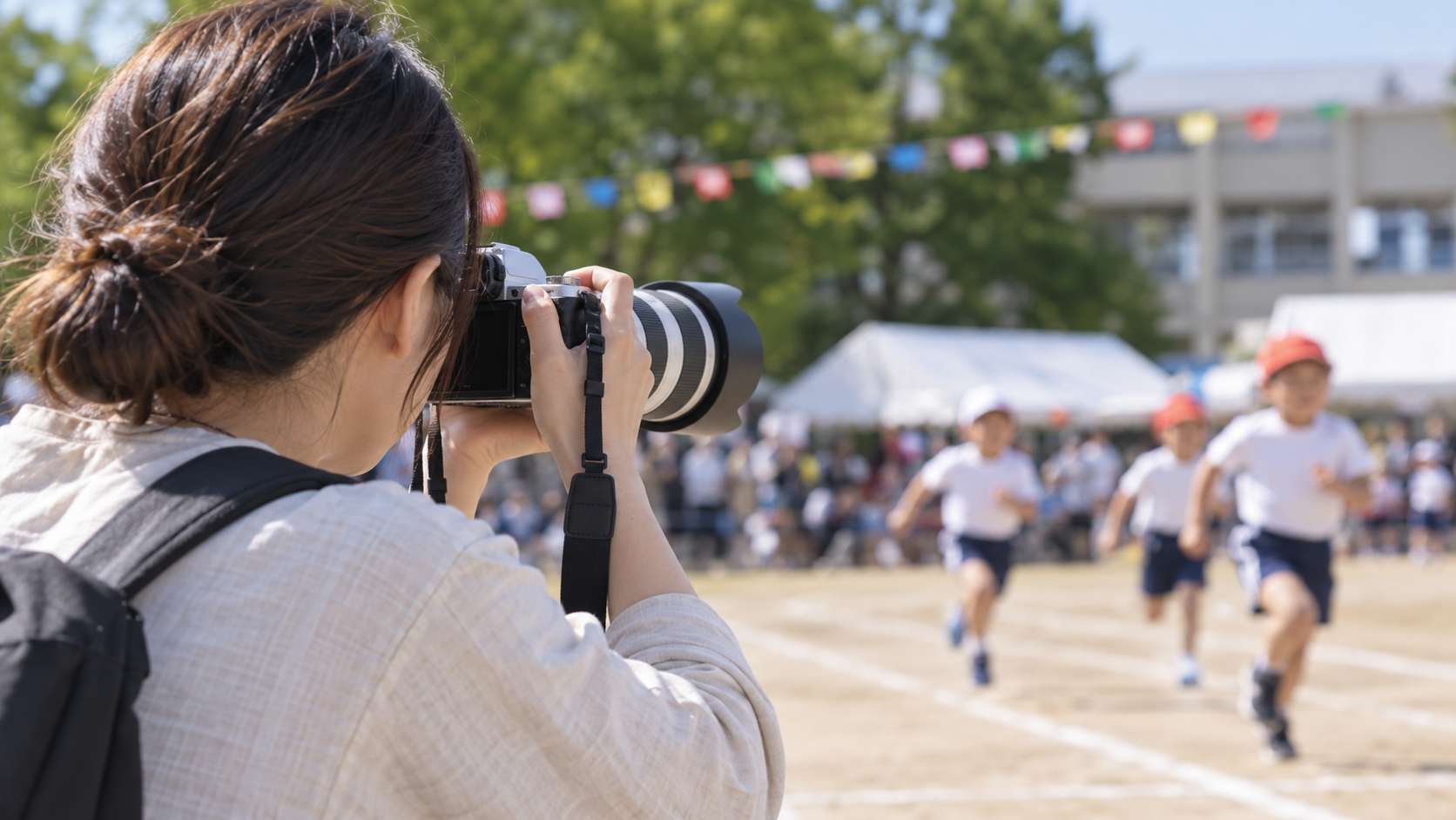 EOS Kiss Mの望遠レンズで運動会の子どもを撮影する女性