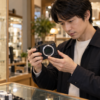 中古カメラ店でミラーレスカメラの状態を確認する日本人男性
