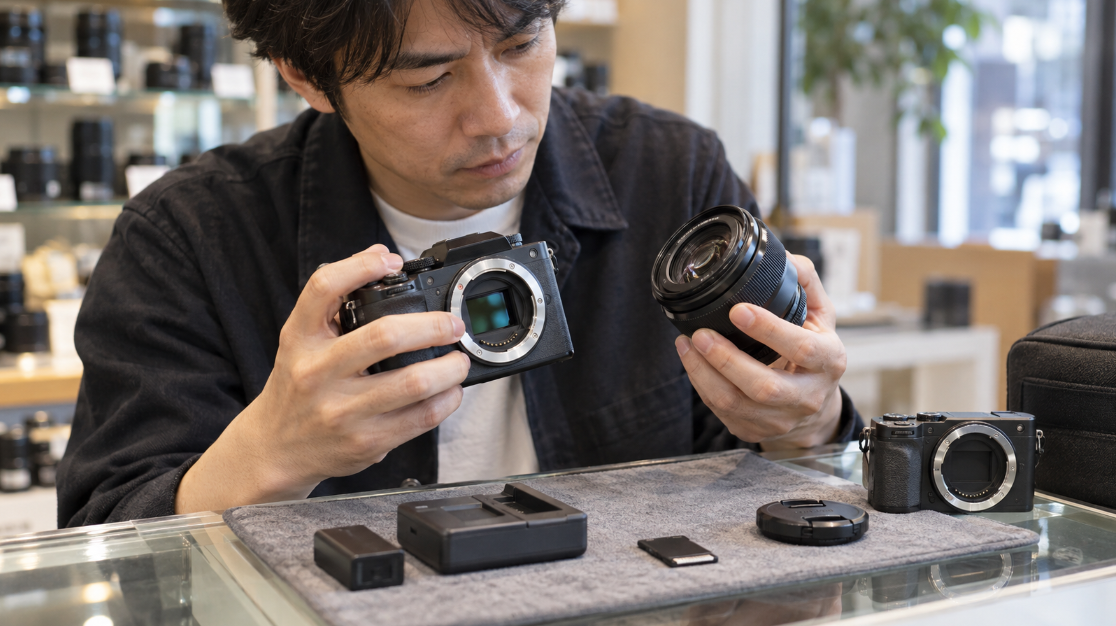 中古カメラ購入前にボディやレンズとバッテリーの状態を確認する男性
