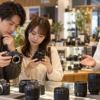 中古カメラと交換レンズを店員に相談しながら比較する日本人の購入者