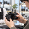 中古ミラーレスカメラの液晶や操作ボタンを店頭で確認する様子
