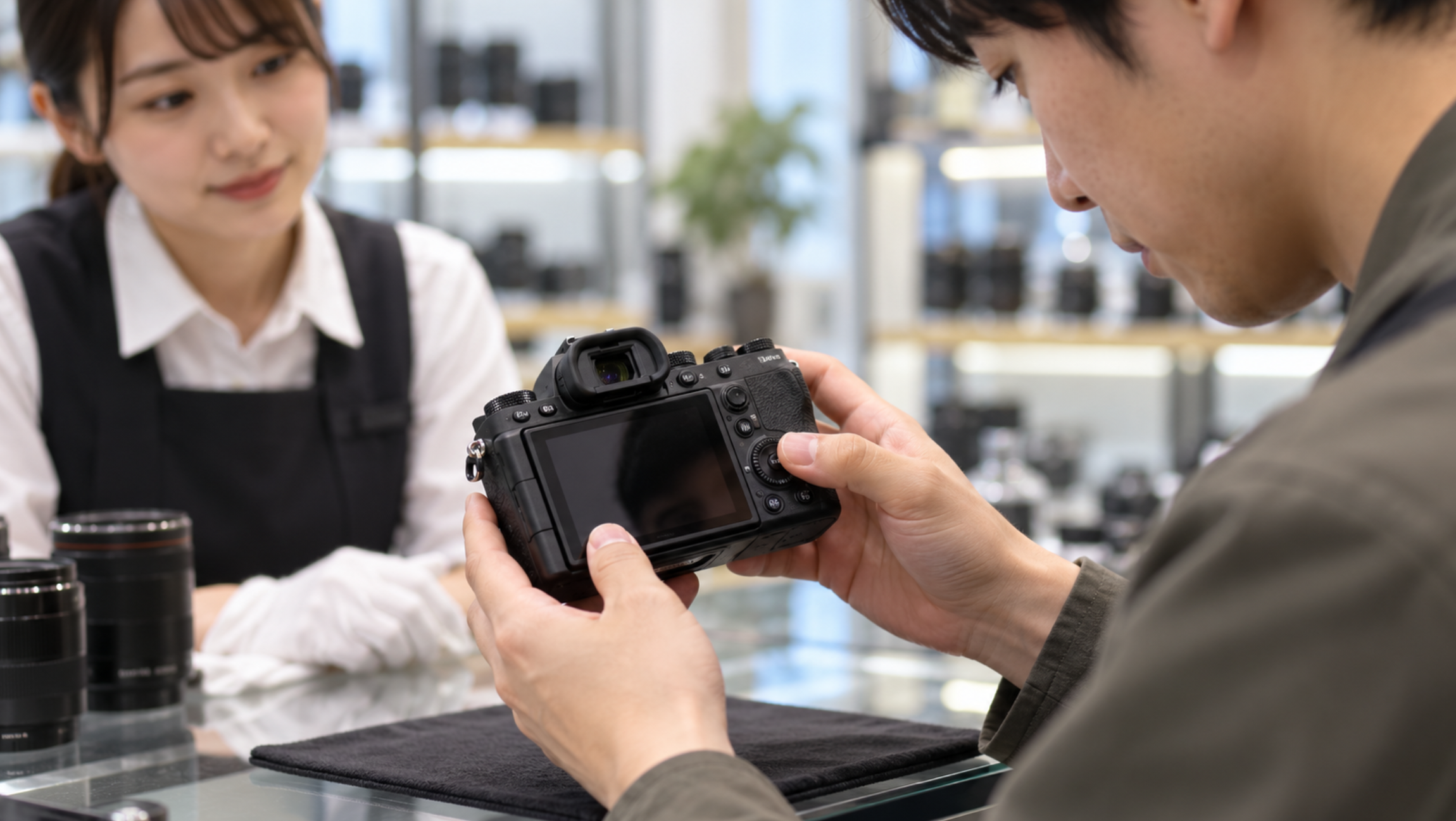 中古ミラーレスカメラの液晶や操作ボタンを店頭で確認する様子