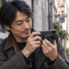 街中でレンジファインダー型カメラを操作する日本人男性