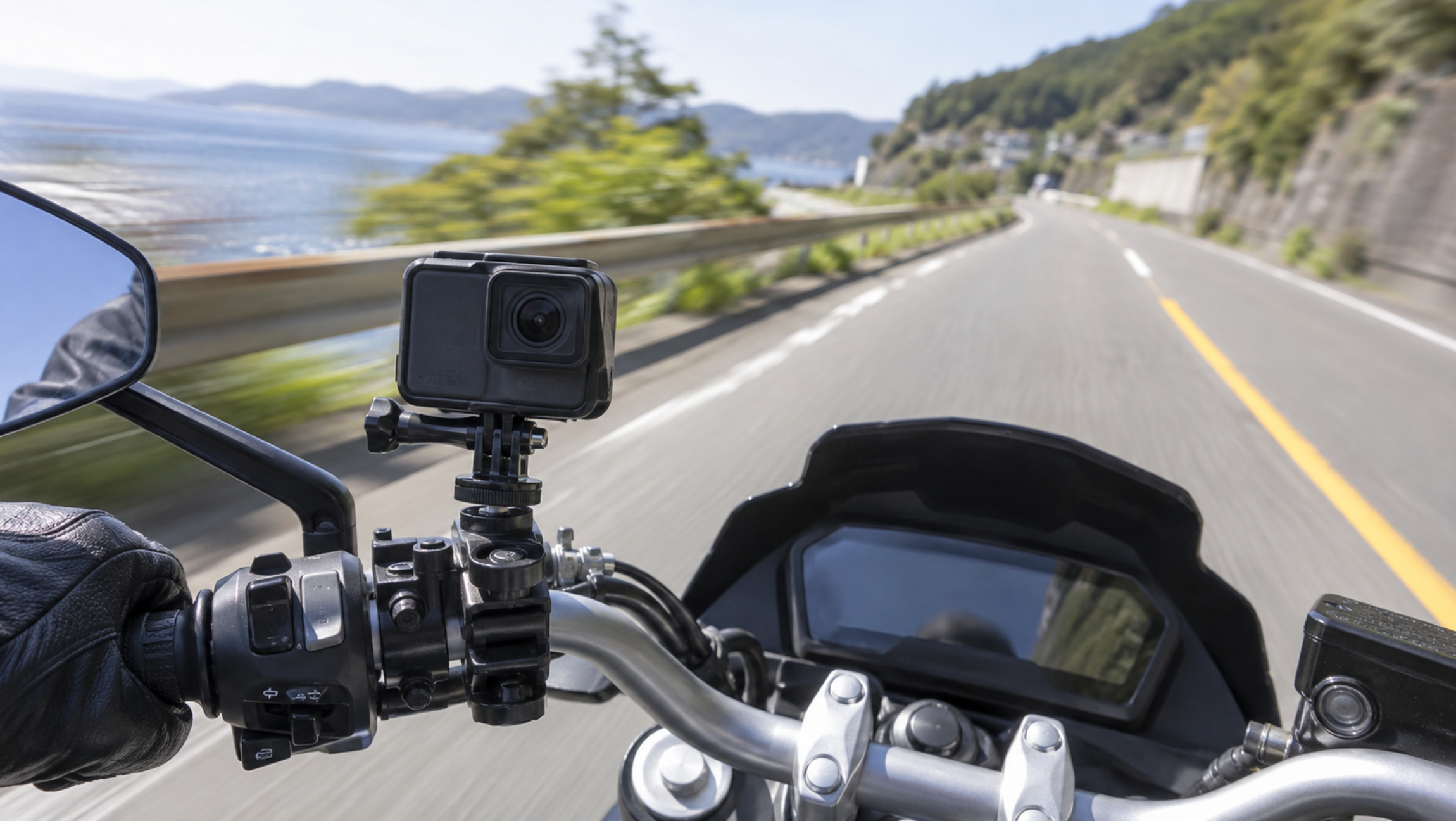 バイクのハンドルに固定したアクションカメラと走行中の道路