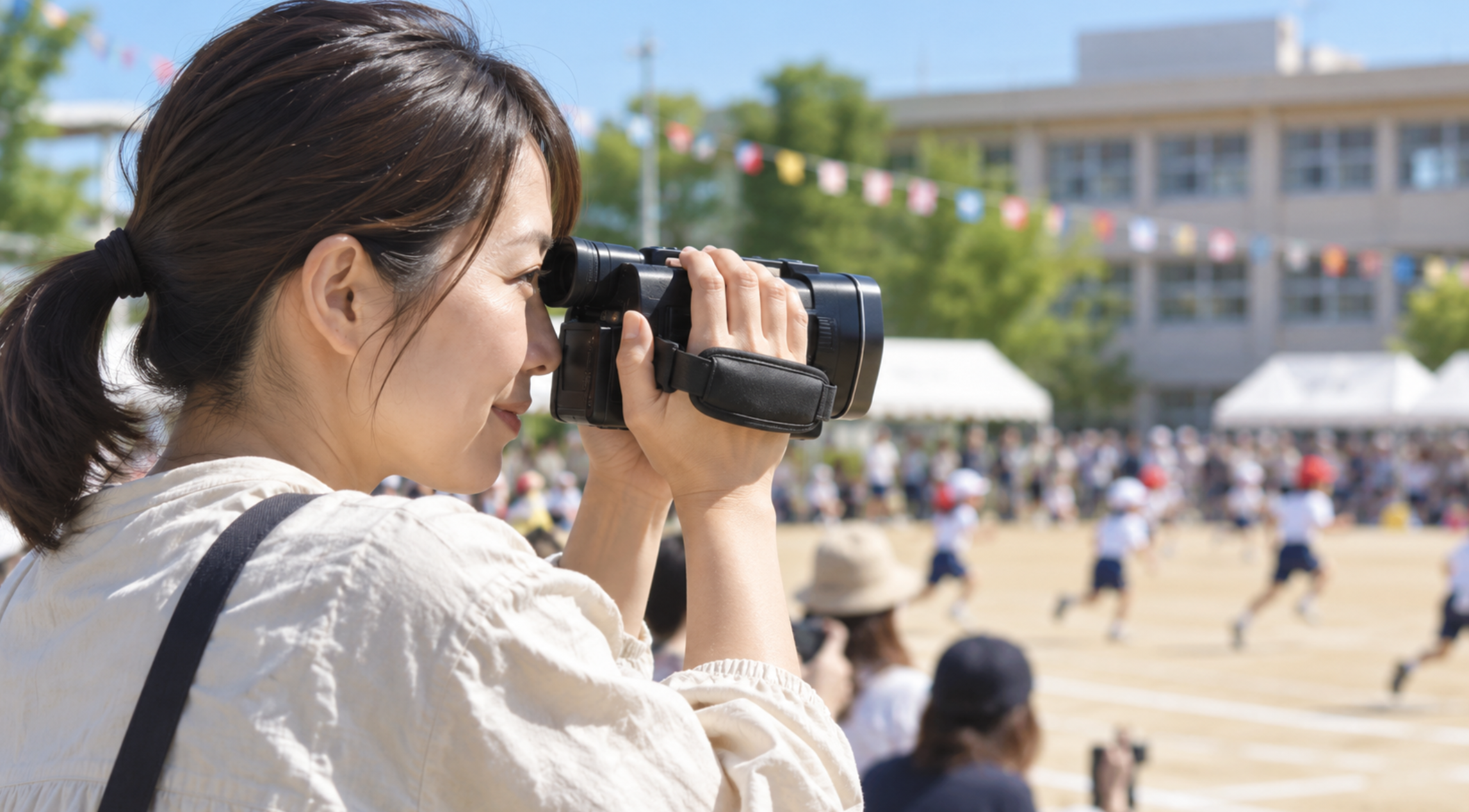 運動会でEVF付きビデオカメラを使って撮影する日本人女性