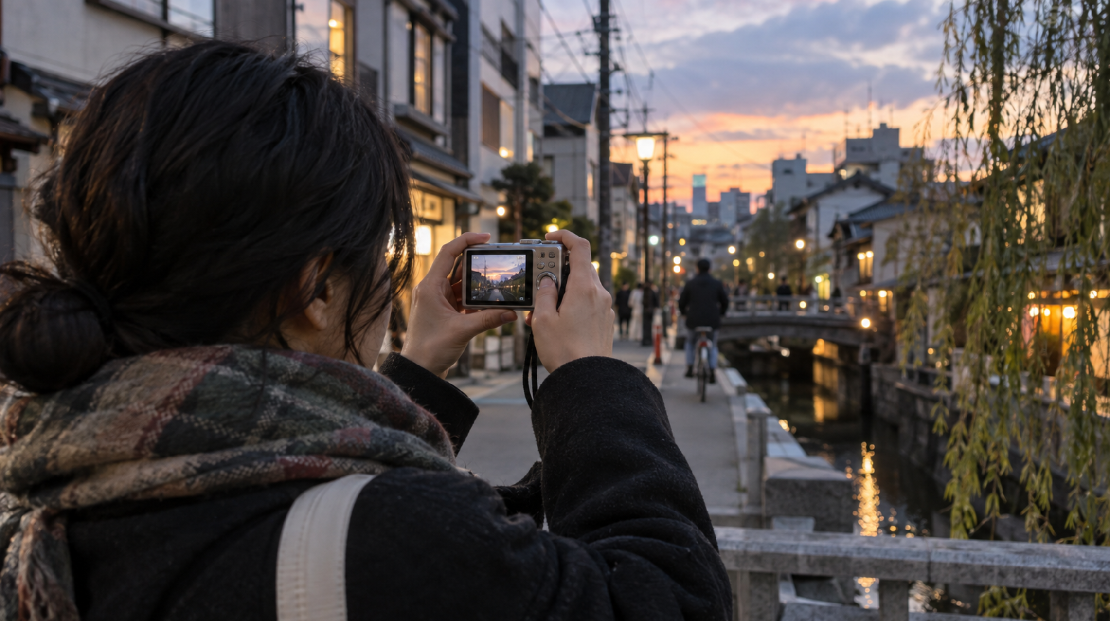 夕暮れの街でレトロな中古コンデジを使って撮影する日本人女性