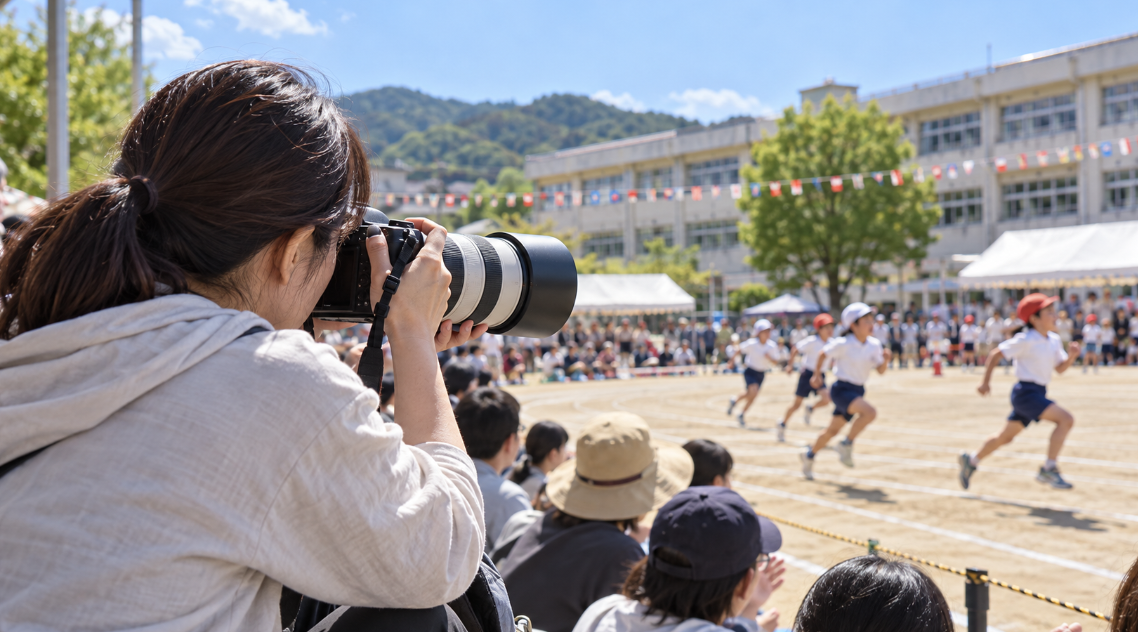 運動会で望遠レンズ付きカメラを使って子どもを撮影する日本人の保護者