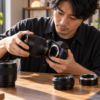 キヤノン用交換レンズとマウントアダプターの互換性を確認しながらミラーレスカメラにレンズを装着する日本人男性