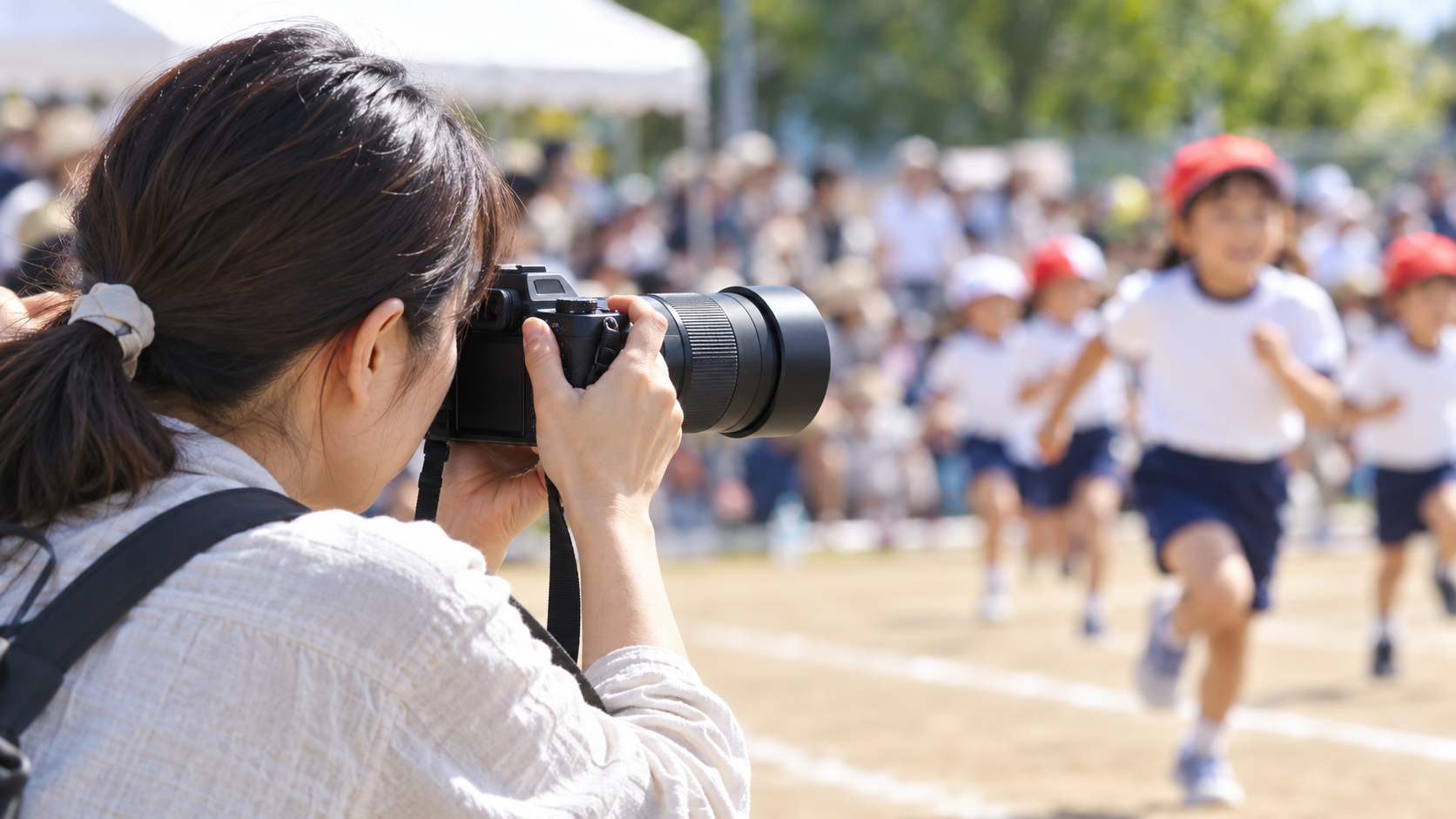 EOS Kiss Mの望遠レンズで運動会の子どもを撮影する女性