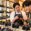 中古カメラ店でミラーレスカメラの状態を確認する店員と購入者