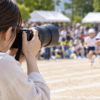 望遠ズームレンズで運動会の子どもを撮影する日本人カメラマン