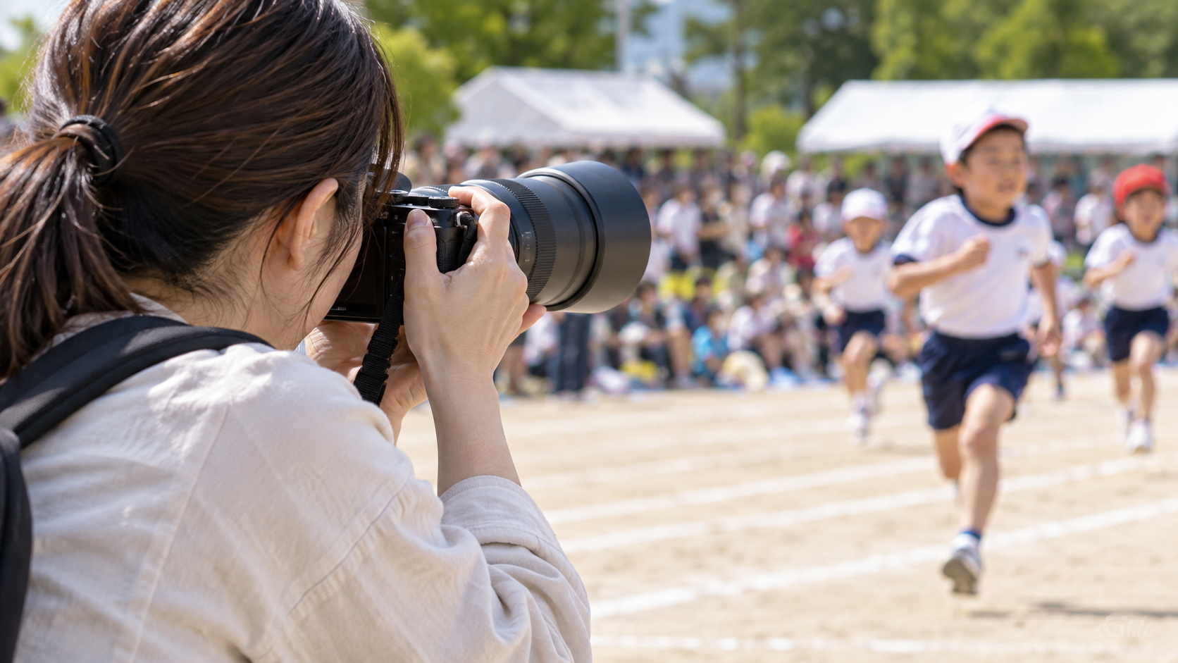 望遠ズームレンズで運動会の子どもを撮影する日本人カメラマン