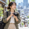 旅行先の街並みで標準ズーム付きミラーレスカメラを持つ日本人女性
